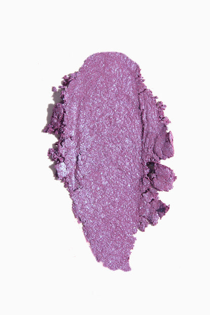 Ripple Super Shock Shadow by ColourPop swatched in a thick oval smear, a creamy lavender-purple eyeshadow with blue iridescent shimmer and metallic finish, spread on a clean white background.