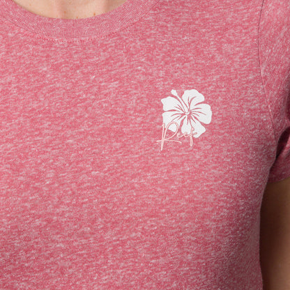 Close-up of a woman's upper torso wearing the mauve Saylor Fitted Tee with a white hibiscus logo, beach-inspired comfort apparel.