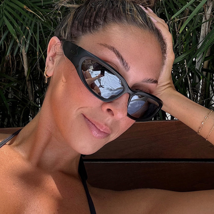 lifestyle - female wearing diff sport side out wrap sunglasses with a matte black frame and grey with silver flash polarized lenses front view