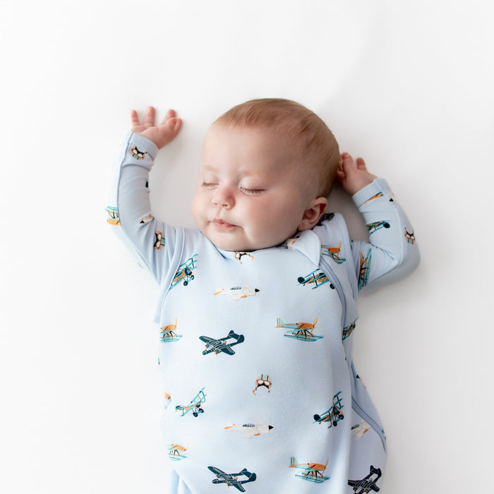 Close up of sleeping infant wearing the Sleep Bag in Take Off 0.5 with a matching long sleeve romper underneath
