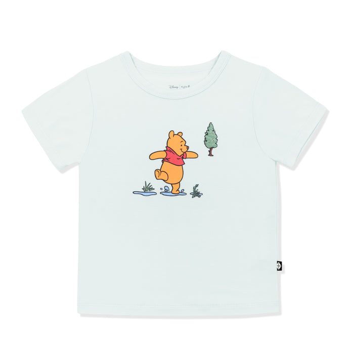 Light green basic tee with the graphic of winnie the pooh walking through puddles in the center of the shirt