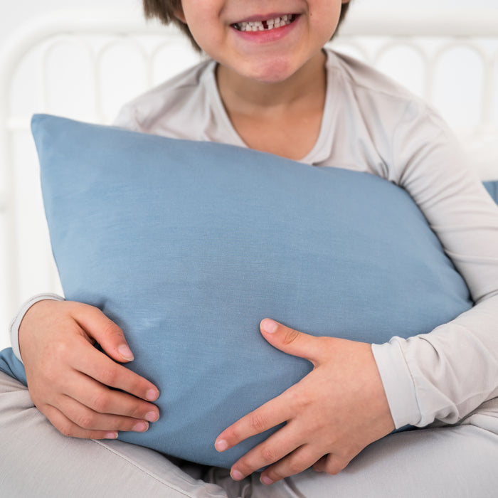 Child holding a blue pillow with a white background