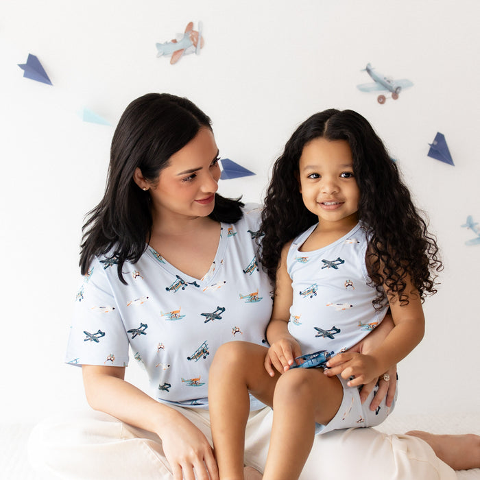 Young girl wearing the Toddler Tank Top in Take Off sitting on her mothers lap who is wearing a matching women's v-neck