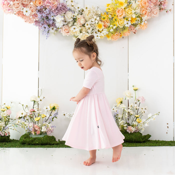 Toddler wearing Kyte Baby Twirl Dress in Sakura pink