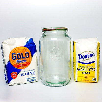 Clear glass jar with Gold Medal flour and Domino sugar packages on a white background