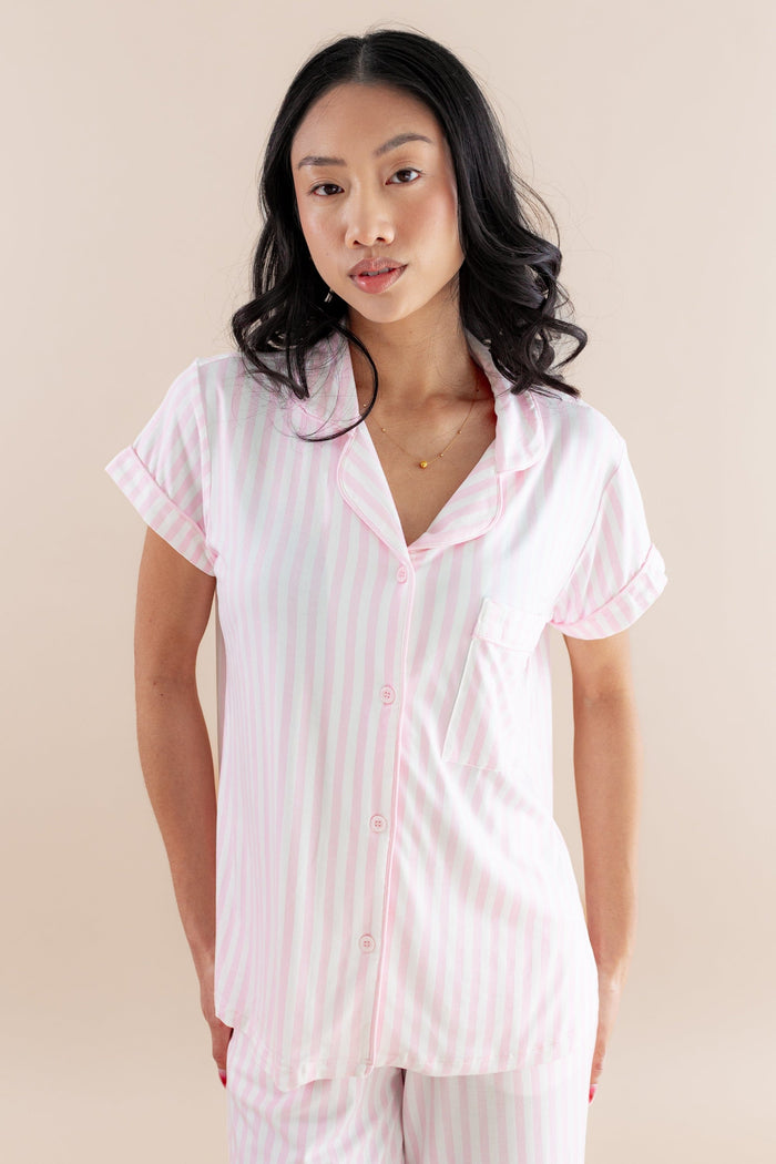 Woman wearing a pink striped pajama set against a beige background