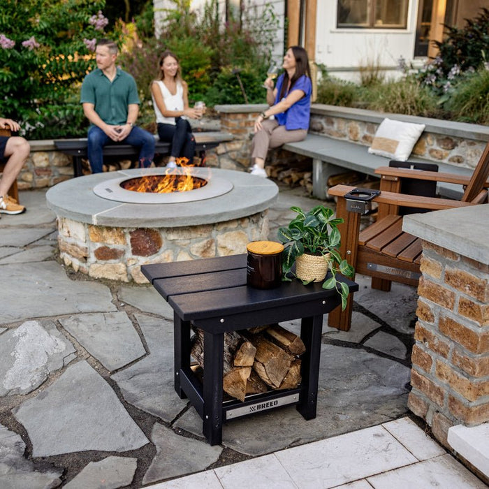 A group of friends hanging out around a Zentro firepit with X Series Furniture, featuring the X Series Side Table