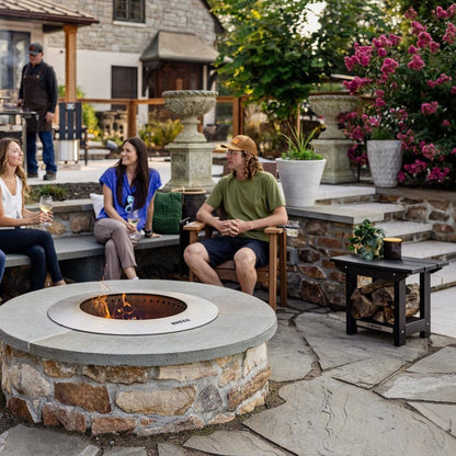 An image of friends hanging out on a patio around the Zentro fire pit, featuring an X Series Side Table