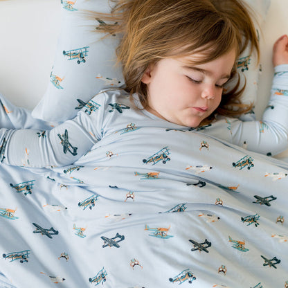 Close up of child sleeping in a bed with the Youth Blanket in Take Off 1.0 on top of them