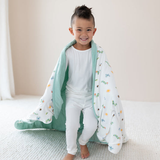 Child in cloud pajamas with Youth Blanket in The Very Hungry Caterpillar™ and Friends 2.5 wrapped around shoulders