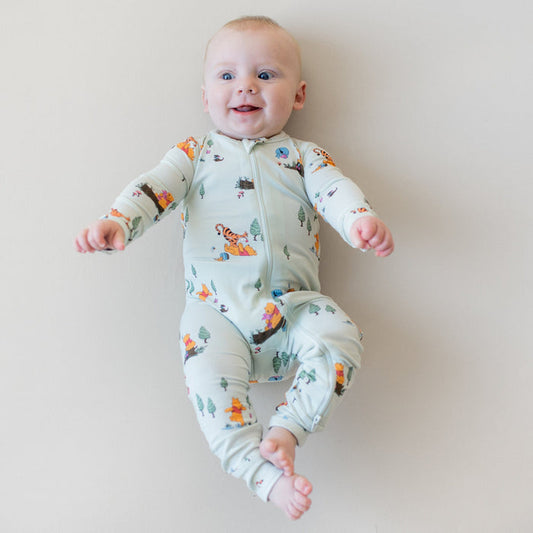 Smiling model wearing the Zippered Romper in Winnie the Pooh Hundred Acre Wood